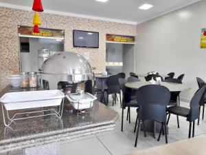 a restaurant with a kitchen and tables and chairs at Hotel Mediterrâneo in Lagarto