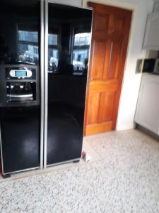 a black refrigerator in a kitchen with a door at Oakland in Portadown