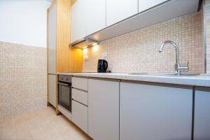 a kitchen with white cabinets and a sink at Apartman DULY LUX in Pržno