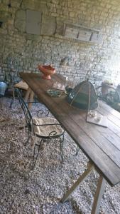 een houten tafel, een stoel, een tafel en een bakstenen muur bij Fig Tree Barn in Gibourne