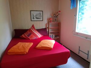 a red bed with two pillows and a window at Bungalow am Waldbad in Schmannewitz