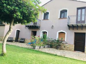 a white house with plants in a yard at Case Vacanze Casa Romana in Lascari