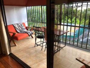 einen Balkon mit einem Tisch, einem Stuhl und einem Sofa in der Unterkunft Cockatoo Studio Apartments in Manuel Antonio