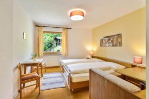 a bedroom with a bed and a desk and a window at Appartements Gabrielli Annamarie in Trodena