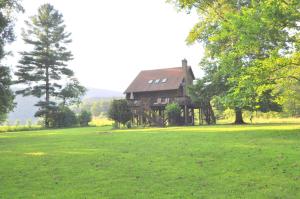a house sitting in a field of green grass at River Valley Cabin - Riverfront Cabin in Morton Grove