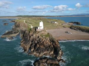an island in the ocean with a white lighthouse at No2 Glan Nodwydd in Pentraeth