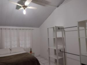 a bedroom with a ceiling fan and a bed at Casa de Férias in Florianópolis