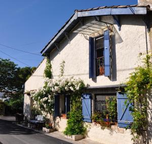 Causses-et-VeyranにあるLa Fontainebleuの青いシャッターと花の白い建物