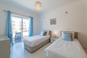 two beds in a white room with a window at Porto de Mós 72 by Destination Algarve in Porto de Mós +58 photos