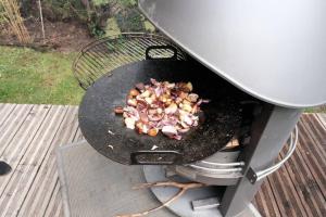 una parrilla con carne y cebollas cocinando en ella en Charmant chalet aux portes d'Epinal, en Épinal