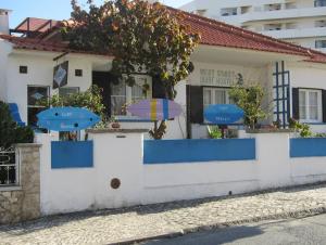 a white and blue building with umbrellas in front of it at West Coast Surf Hostel in Areia Branca