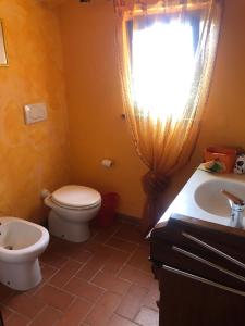 La salle de bains est pourvue de toilettes, d'un lavabo et d'une fenêtre. dans l'établissement Monolocale La Mimosa, à Elmo