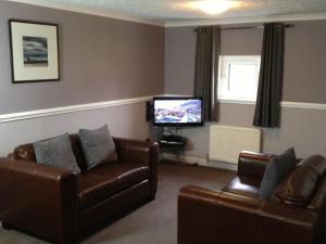 a living room with two couches and a flat screen tv at Home Farm Apartments in Portree