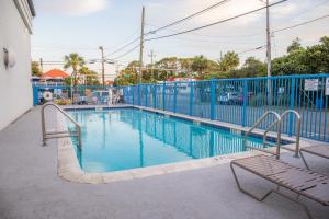 una piscina con due panchine accanto a una recinzione blu di Sandcastle Inn a Tybee Island