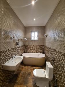 ein Badezimmer mit einer Badewanne, einem WC und einem Waschbecken in der Unterkunft Greystone Mansion in Accra