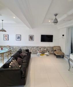 een woonkamer met een zwarte bank en een tv bij Greystone Mansion in Accra