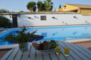 a table with a bowl of fruit next to a swimming pool at Il Cigno Reale - White - Rooms Leasing tuoristic Ragusa in Chiaramonte Gulfi