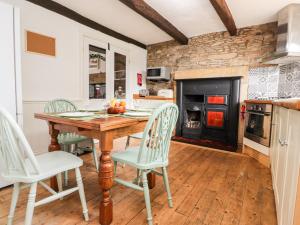 uma cozinha com uma mesa e cadeiras e uma lareira em Jam Pot Cottage em Preston