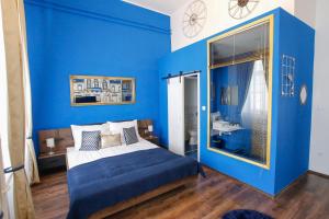 a blue bedroom with a bed and a large window at Uránia Apartmanház in Eger