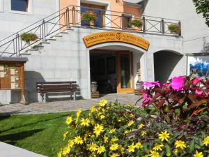 苏特廖Albergo Diffuso Sutrio Zoncolan的前面有长凳和鲜花的建筑