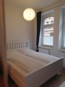 ein Schlafzimmer mit einem weißen Bett und einem Kronleuchter in der Unterkunft Ferienwohnung "Kleiner OTTO" in Erfurt