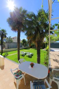 einen weißen Tisch und Stühle auf einer Terrasse mit Palmen in der Unterkunft Apartments Vedrana in Zadar