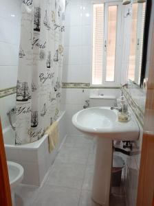 a white bathroom with a sink and a shower curtain at Piso Grande Mercado Central Alicante in Alicante