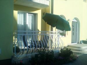 a balcony with chairs and an umbrella on a house at Ana Rooms in Krk