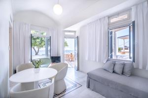 a white living room with a table and a couch at Xenones Filotera in Imerovigli