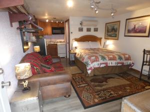 een slaapkamer met een bed en een bank bij Yellowstone Motel - Adults Only - All rooms have kitchens in West Yellowstone