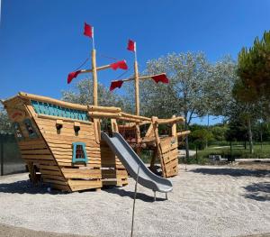 a wooden playground with a slide in a park at Pareus Beach Resort in Caorle