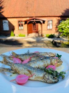 a plate of fish on a table with a house at Dworek Mazurski Ruś in Ruś