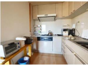 una pequeña cocina con armarios blancos y microondas en Monzen House Dormitory type- Vacation STAY 49374v, en Kasama