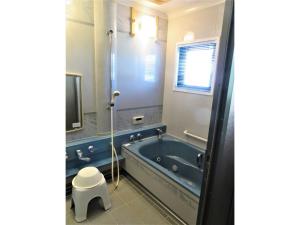 Monzen House Dormitory type- Vacation STAY 49374v في Kasama: حمام مع حوض استحمام أزرق وتلفزيون