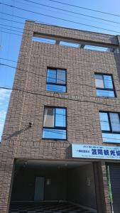 un edificio alto de ladrillo con ventanas azules. en Monzen House Dormitory type- Vacation STAY 49374v, en Kasama