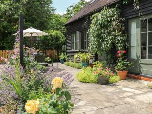 a garden in front of a house with flowers at The Barn at Sandhole Cottage in Tonbridge