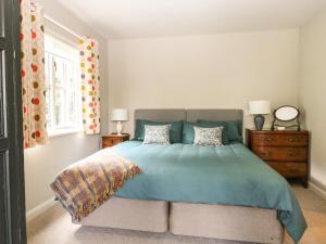 a bedroom with a bed with a blue comforter at The Barn at Sandhole Cottage in Tonbridge