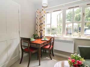 a dining room with a table and chairs and windows at The Barn at Sandhole Cottage in Tonbridge