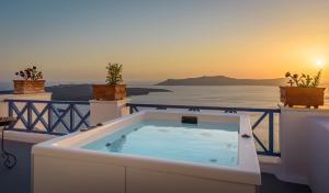 a hot tub on a balcony with a view of the ocean at Golden Grey Goose in Fira
