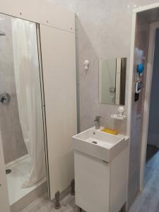 baño blanco con ducha y lavamanos en Evergreen Hostel Krakow, en Cracovia
