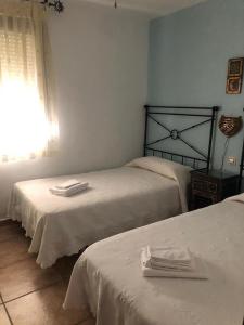 een slaapkamer met 2 bedden met witte lakens en een raam bij APARTAMENTO ZAHARA DE LOS ATUNES in Zahara de los Atunes