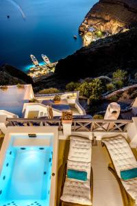 a pool with chairs and a view of the ocean at Golden Grey Goose in Fira