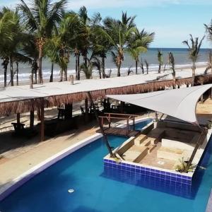 a swimming pool next to a beach with palm trees at ALIZE CUMBUCO in Cumbuco