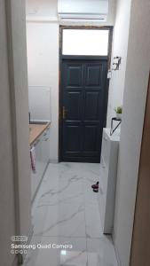 a kitchen with a black door and a white tile floor at Studio Apartman Malkoc in Bihać +3 photos