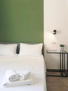 a white bed with towels on it with a side table at ISTAI Cagliari City Center Rooms in Cagliari