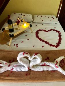 a bed with a heart drawn on it with a bottle of wine at Chalé Suíço - Chalés Belo Monte - Sítio Belo Monte in Pacoti