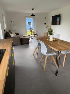 a dining room and living room with a wooden table and chairs at Deluxe Ferienwohnung für 4 bis 6 Personen Ladestation E-Auto & E-Bike in Lancken-Granitz