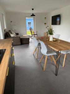 a dining room and living room with a wooden table and chairs at Villa Frankenstein - Deluxe Ferienwohnung mit Ladestation E-Auto & E-Bike in Lancken-Granitz