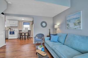 a living room with a blue couch and a kitchen at Odysea in Hampton