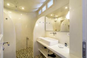 a white bathroom with a sink and a mirror at Golden Grey Goose in Fira